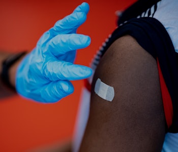 28 July 2021, Brandenburg, Potsdam: A vaccinator sticks a plaster on the student's arm after the vac...