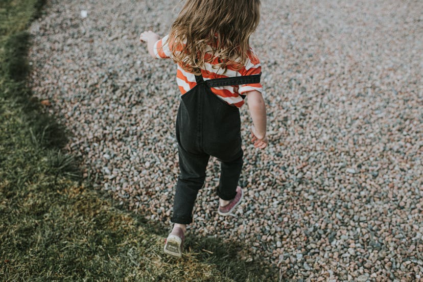 little girl skipping along a gravel road