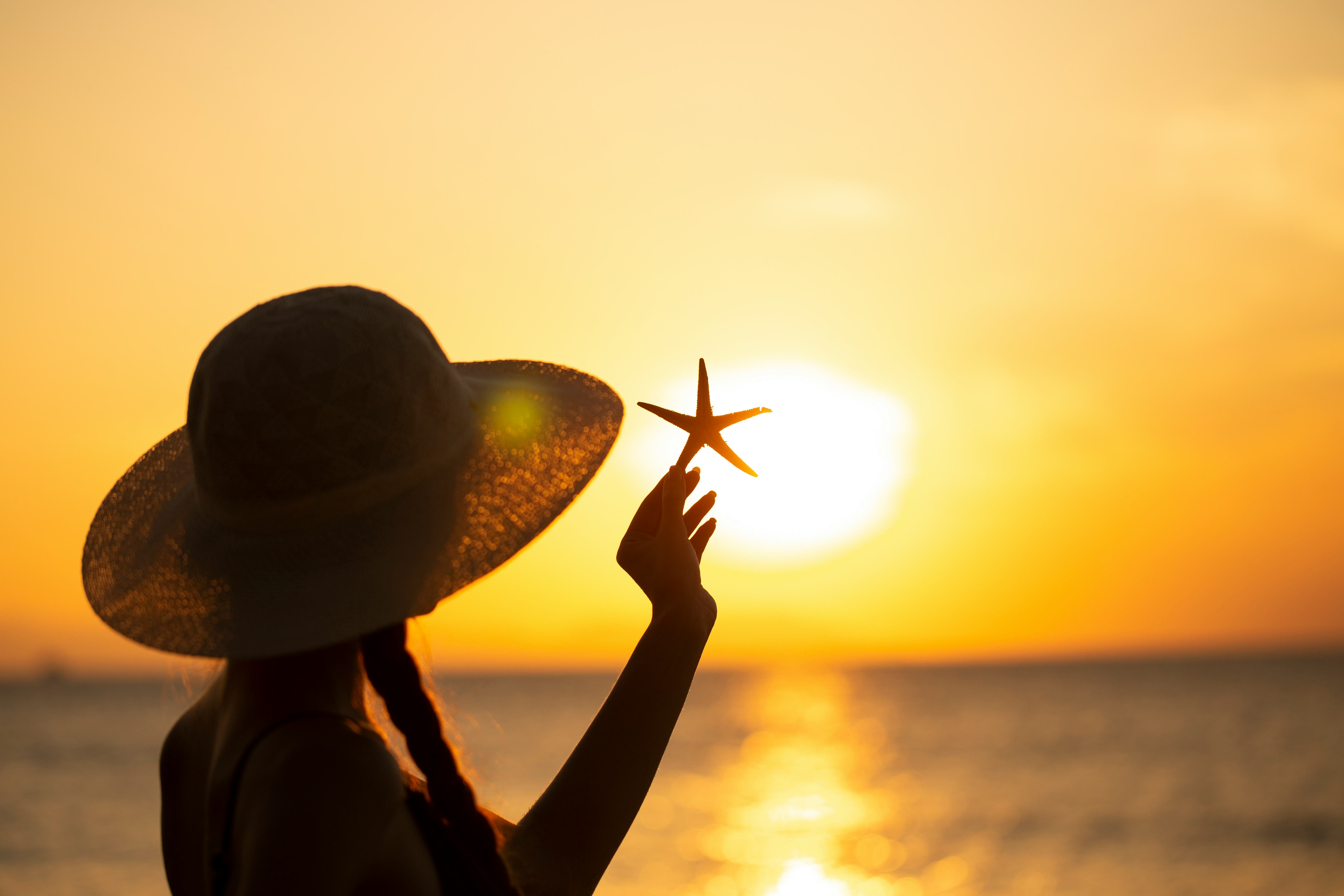 young woman in hat with starfish on the beach