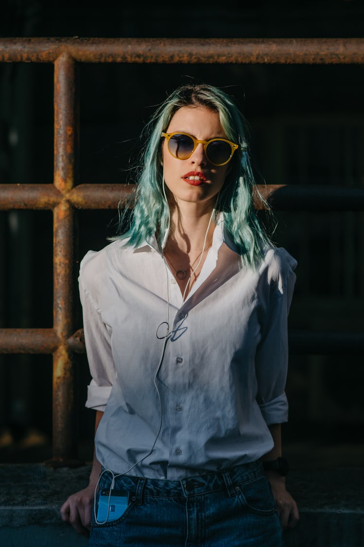Young woman with blue hair looking at camera, after reading about the emotional meaning of the Augus...