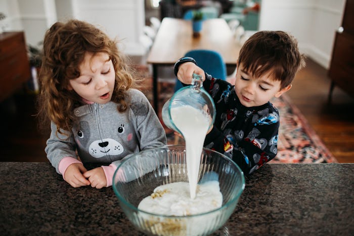 two kids pouring batter into a bowl