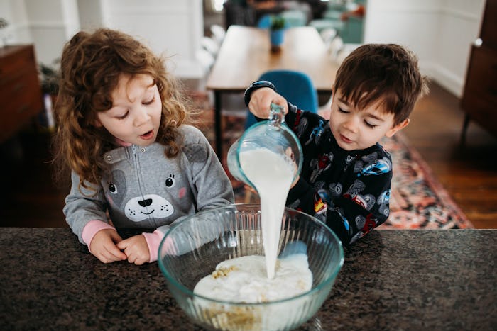 two kids pouring batter into a bowl