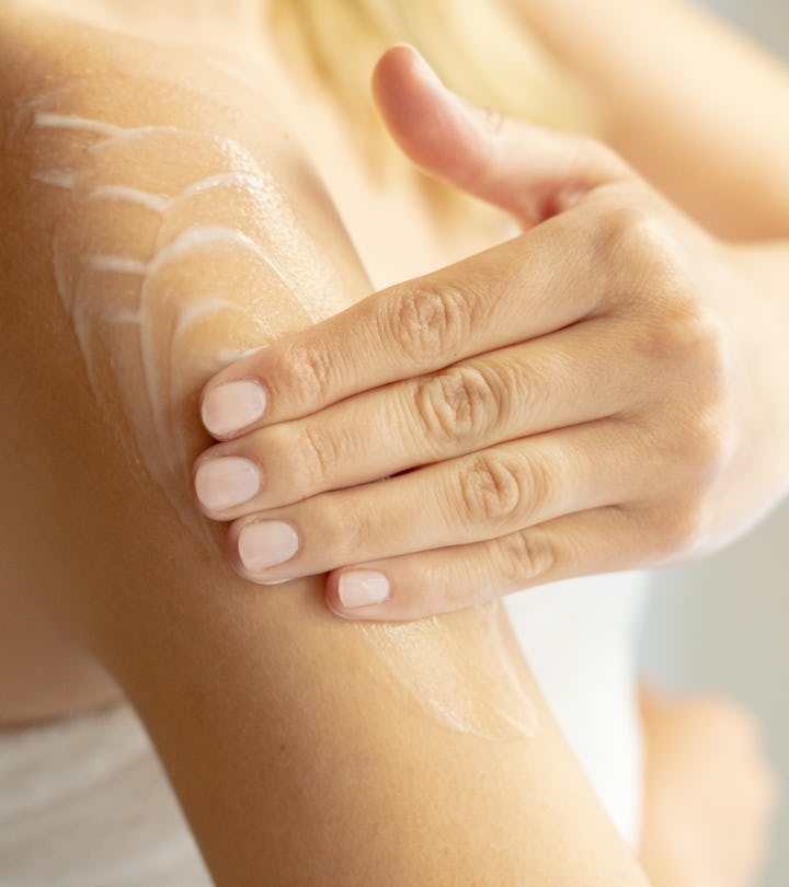 woman putting lotion on arm after shower