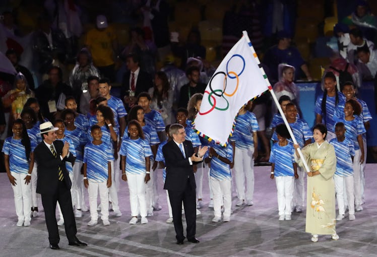 The governor of Tokyo Yuriko Koike waves the Olympic Flag as IOC President Thomas Bach and the mayor...