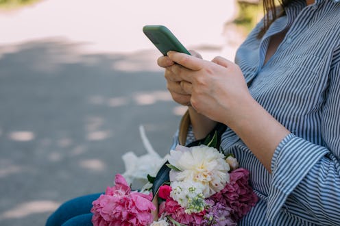 An unrecognizable plus size woman sitting in the park and using her mobile phone