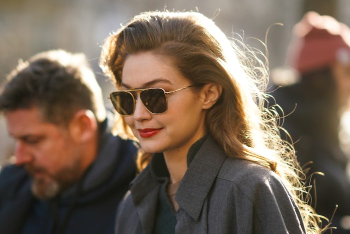 PARIS, FRANCE - FEBRUARY 26: Gigi Hadid wears sunglasses, a gray jacket, a green wool pullover, outs...