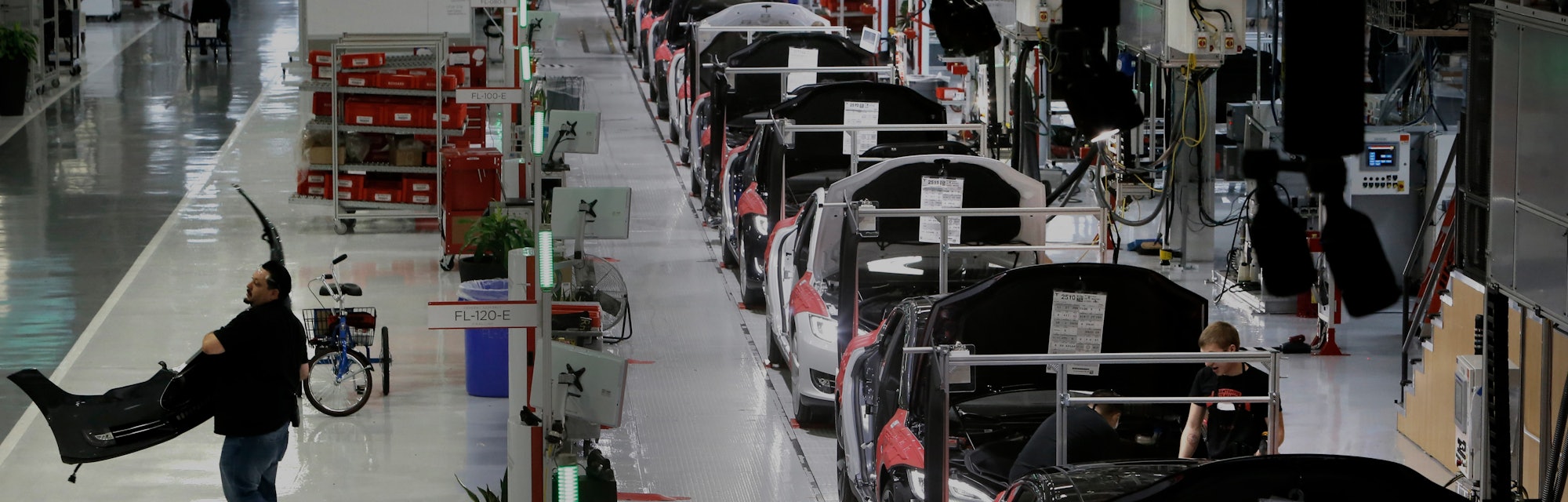 A worker carries a front end part along the assembly at Tesla Motors, California's only full-scale a...