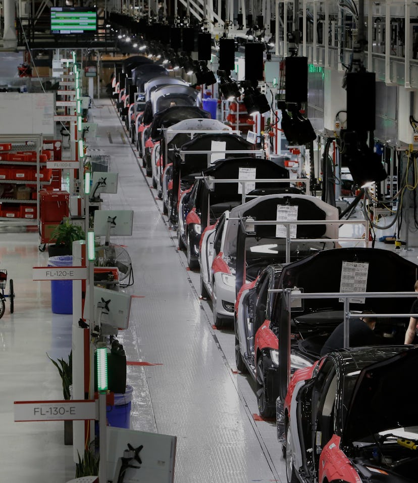 A worker carries a front end part along the assembly at Tesla Motors, California's only full-scale a...