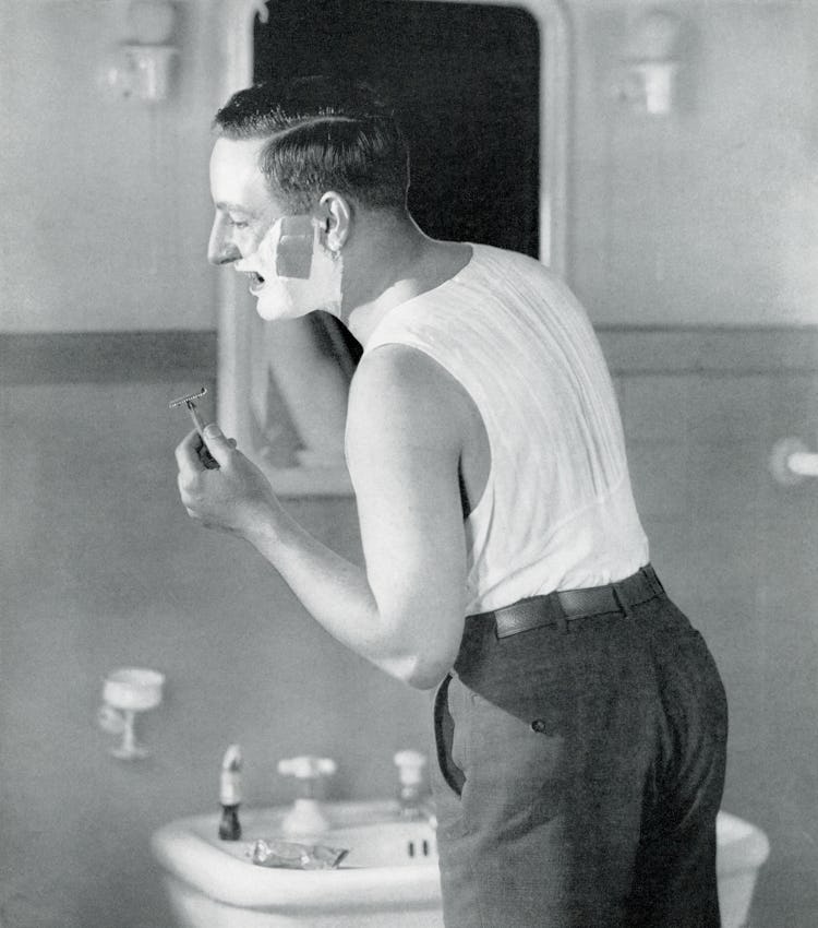 Businessman standing in front of a mirror shaving, from a 1920s guide to salesmanship and selling; s...