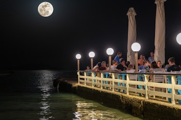 24 June 2021, Tolo, Greece: This is a photo of people eating at an outdoors restaurant next to the s...