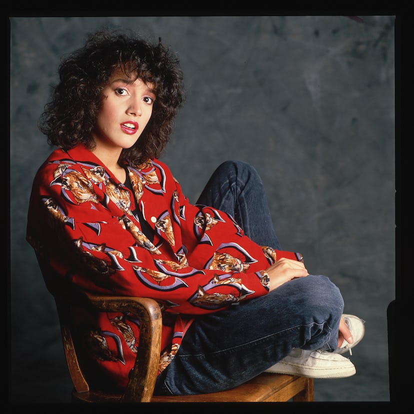 Jennifer Beals with voluminous curly hair and bangs, a signature '80s hair look. 