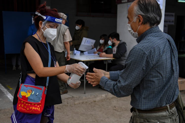 A man sanitizes his hands before casting his ballot in a constitutional referendum voting at a polli...