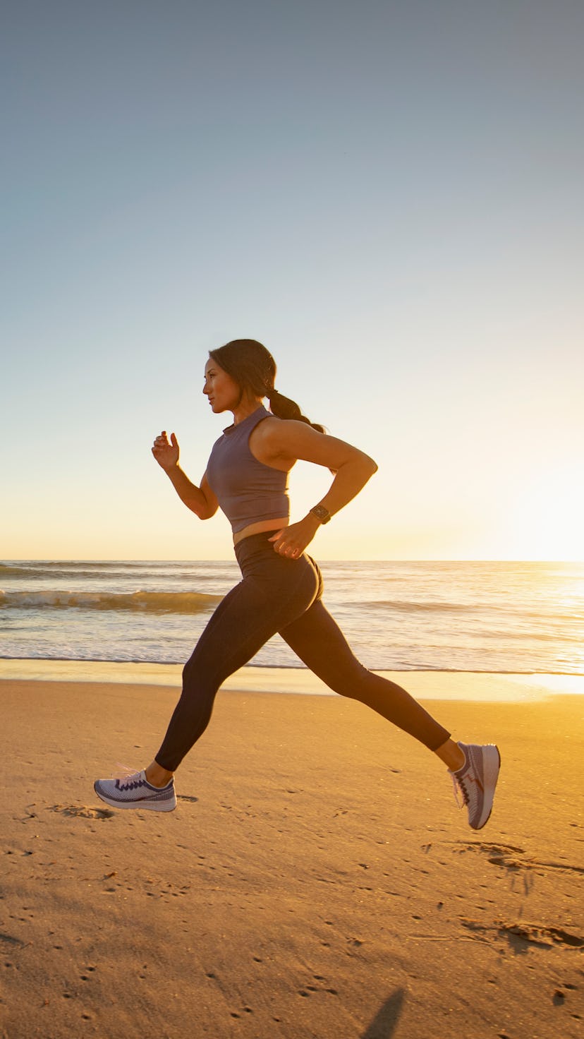 A woman goes running on the beach. You don't need to go swimming to get in a beach workout.