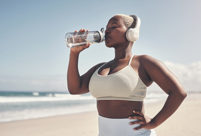 A person drinks from their water bottle during their beach workout. You don't have to swim to work o...