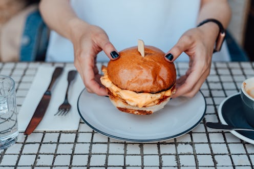 A woman eats a cheeseburger. Wondering why am i craving meat? Experts explain signs and reasons you'...