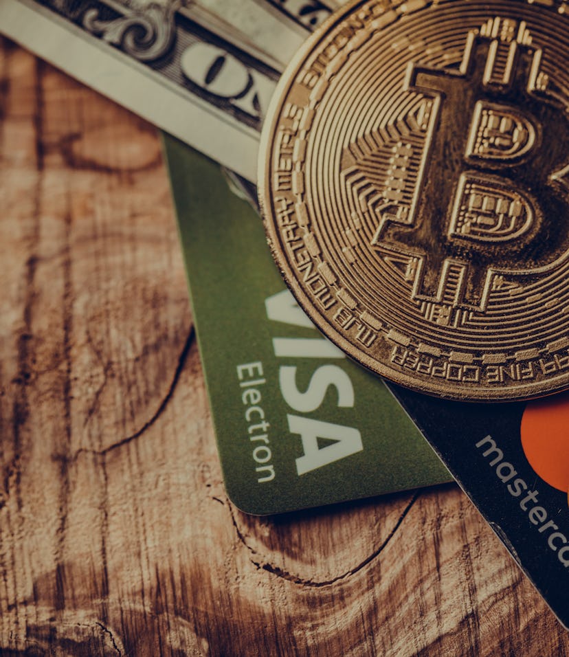 One coin of bitcoin on a black brown with dollars and the cards Visa , Mastercard