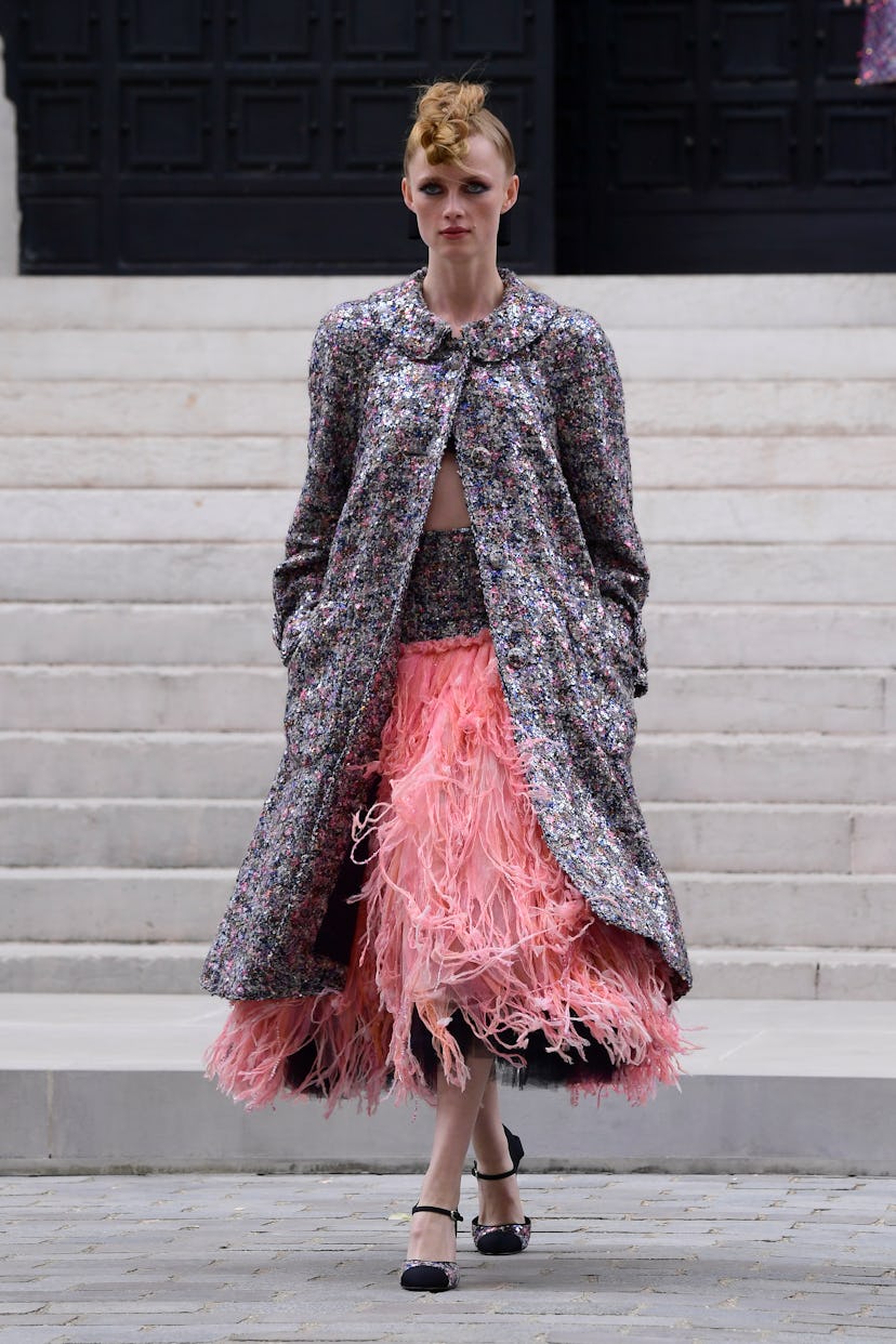 A model wearing Chanel's grey coat and pink dress at the Fall 2021 Couture Fashion Week