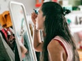 a young woman sitting in front of her bedroom mirror, learning how to apply makeup