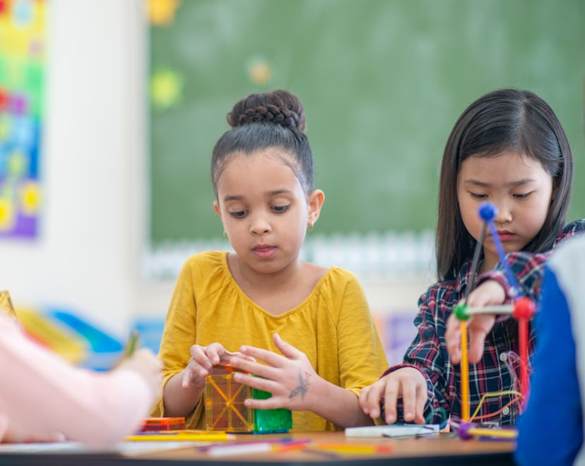 A diverse group of students build structures with colourful materials.