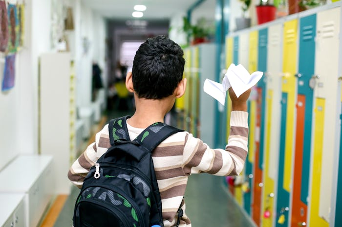 Unrecognizable boy in a school hallway. About 9-10 years old, mixed race male.