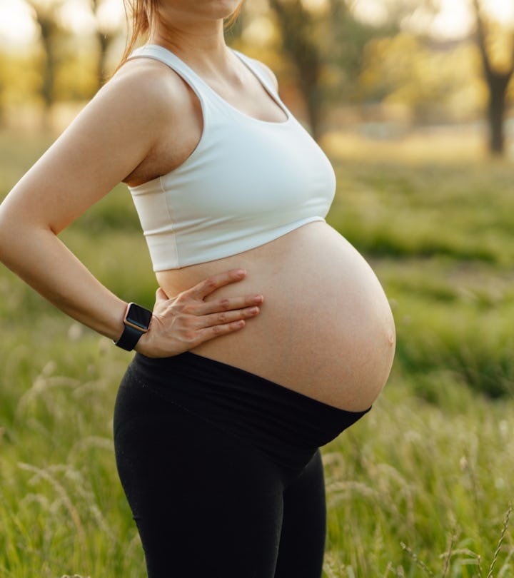 Portrait of pregnant unrecognisable woman relaxing in park. 