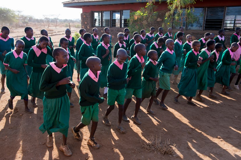 Kenyan school children dancing in school yard in green uniforms and pink collars