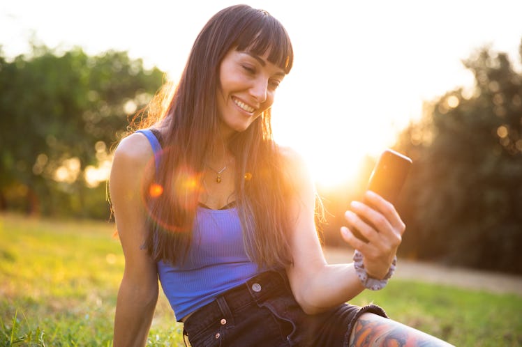 Young women using smartphone outdoor at sunset, having the best week of August 30, 2021, per her zod...