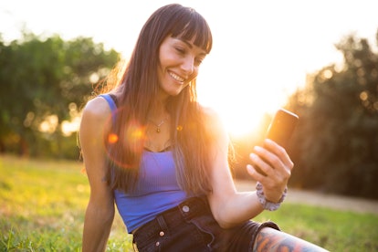 Young women using smartphone outdoor at sunset, having the best week of August 30, 2021, per her zod...