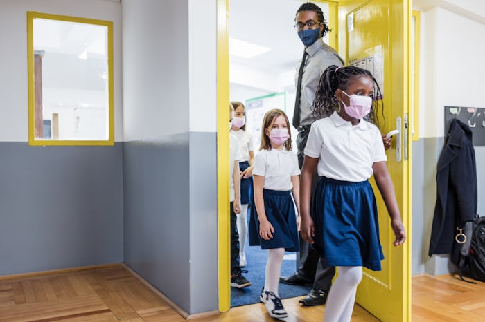 Back to school. Primary School Teacher and students entering a classroom
