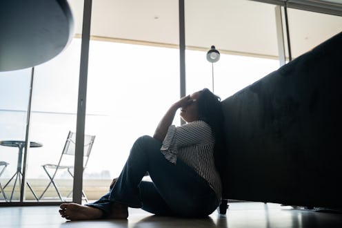 Depressed mature woman sitting on the ground at home