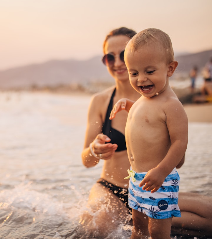 Mother with her little boy son on vacation, they are having fun on the beach in sunset.