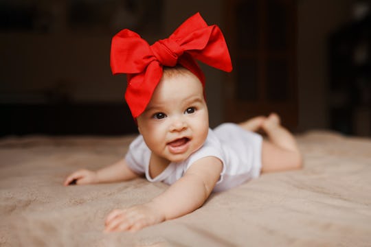 Little beautiful girl lying on the bed bow on her head smiling happy 3-4 month