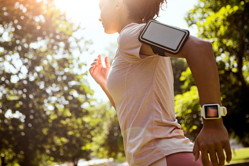 A person wears their phone on their arm as they go for a run in a park. Yes, you can work out while ...