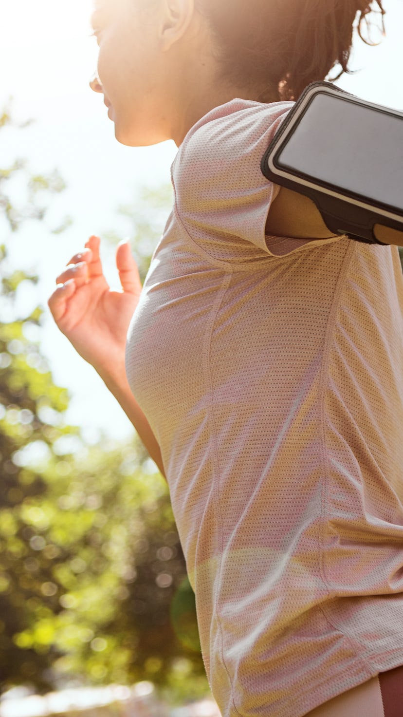 A person wears their phone on their arm as they go for a run in a park. Yes, you can work out while ...
