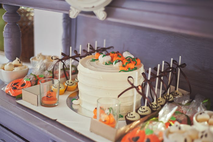 Dessert table with Halloween-themed cake, cake pops, cookies, and cupcakes