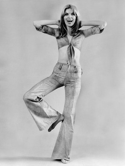 A woman wears flared jeans and a tie-front top in an advertisement in the 1970s, Germany.