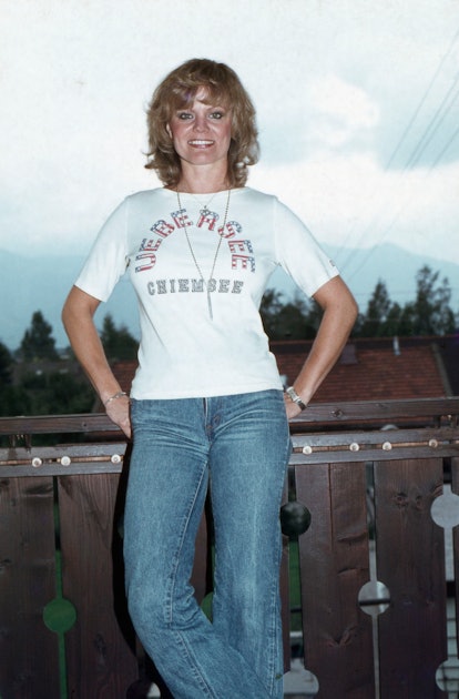 German actress Christiane Ruecker wears bootcut jeans and a graphic white tee, Germany, 1970s. 