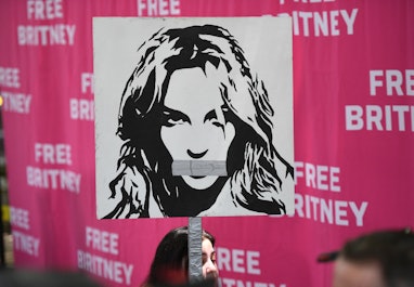 A woman holds a poster of Britney with her mouth taped shut as fans and supporters gather outside th...