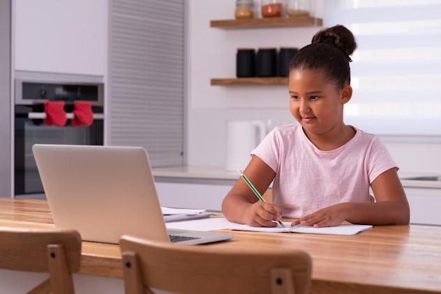 A young student watching a lesson online and studying from home. Girl using the laptop for online le...