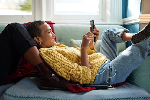 Smiling woman text messaging on smart phone, using the smiling emoji the wrong way