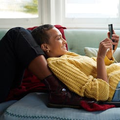 Smiling woman text messaging on smart phone, using the smiling emoji the wrong way