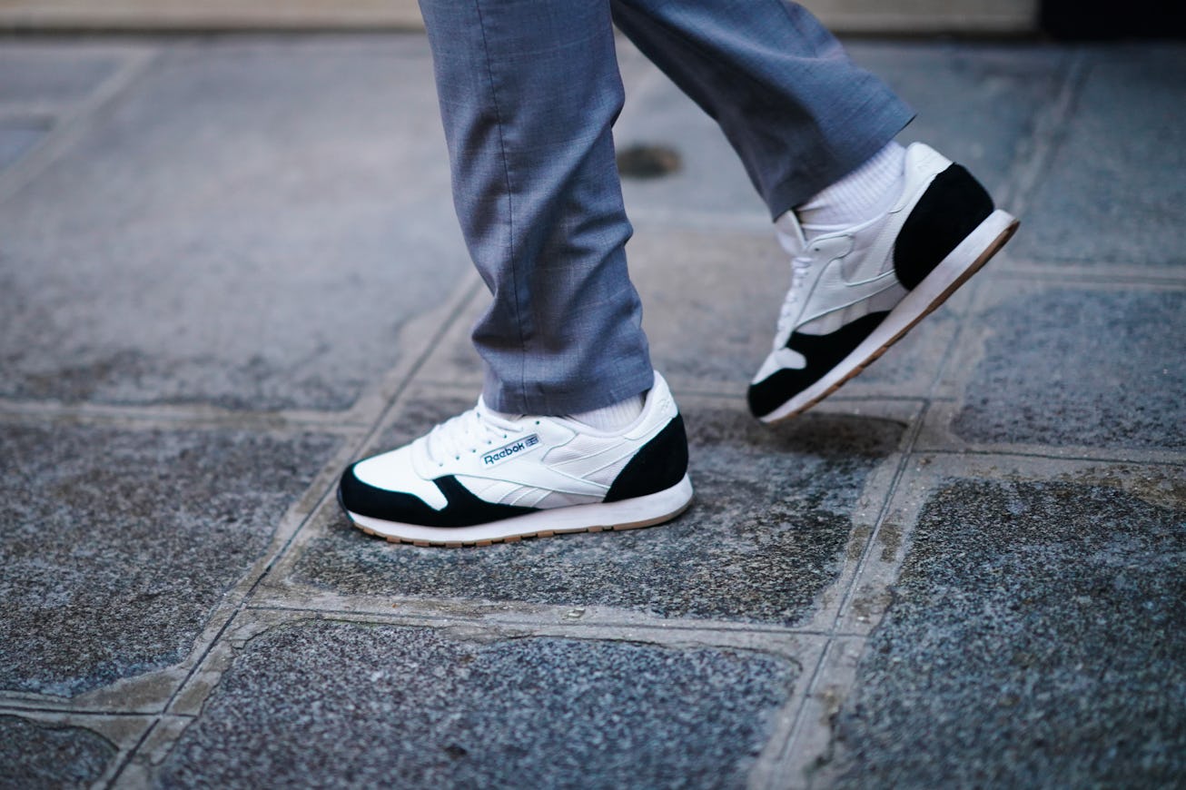 PARIS, FRANCE - DECEMBER 09: A passerby wears gray pants, Reebok black and white sneakers shoes, on ...