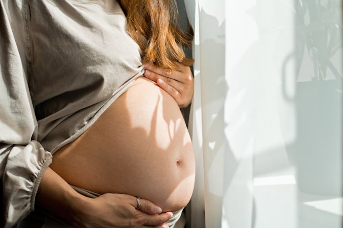 Pregnant woman standing near window in the morning