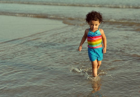 Toddler walks on beach.