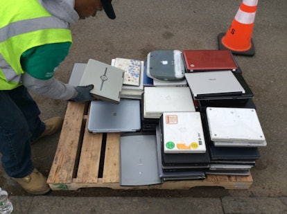 A man places a laptop computer on a skid at the Safe Disposal program for recycling electronics.