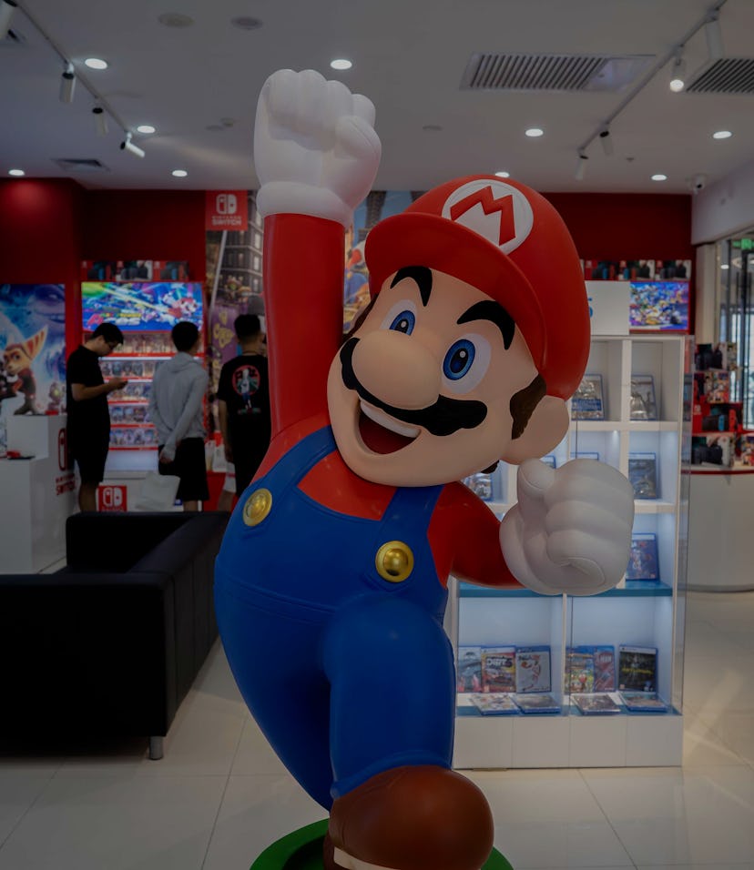TIANJIN, CHINA - 2021/07/20: A cartoon figurine of Super Mario Bros. stands in front of a Nintendo S...