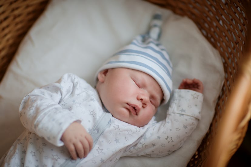 Beautiful baby in a white knitted scarf and cap, sleeping sweetly in a cradle