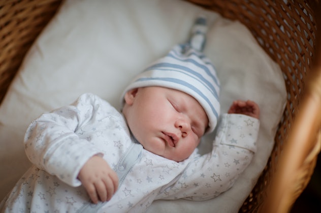 Beautiful baby in a white knitted scarf and cap, sleeping sweetly in a cradle