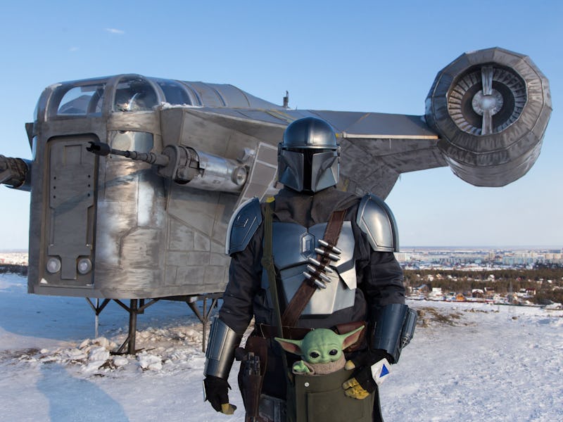 A man wearing a costume of the StarWars protagonist Din Djarin poses in front of a giant replica of ...