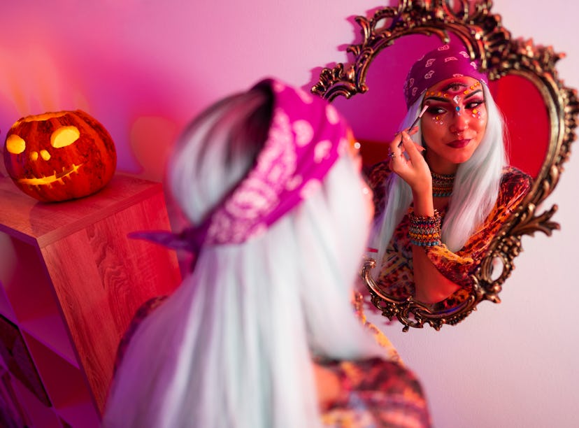 A young woman puts on makeup before taking a picture that would go well with Halloween 2021 Instagra...